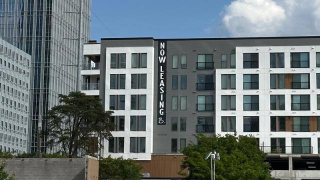 "Now Leasing" sign on mixed-use multifamily building in Sun Belt